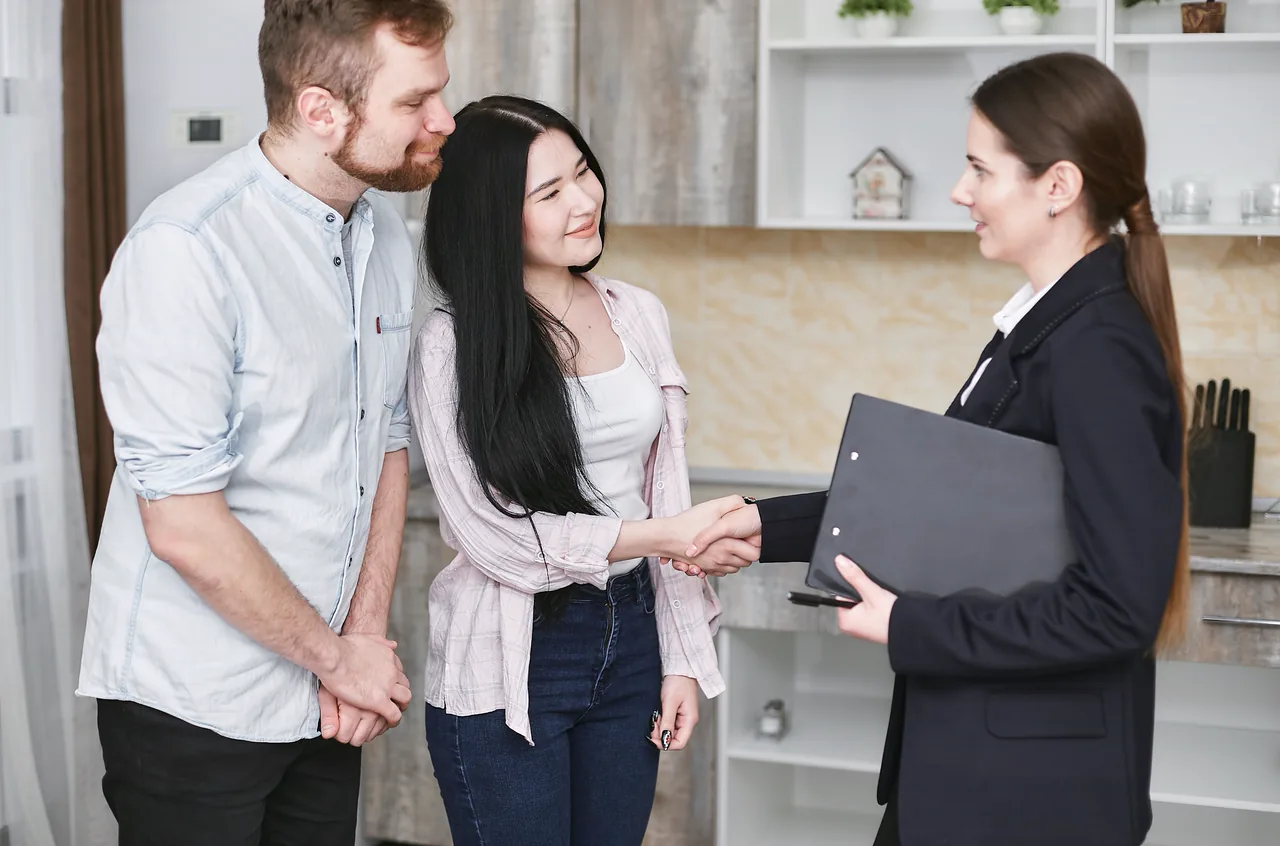 A real estate agent with a smiling young couple